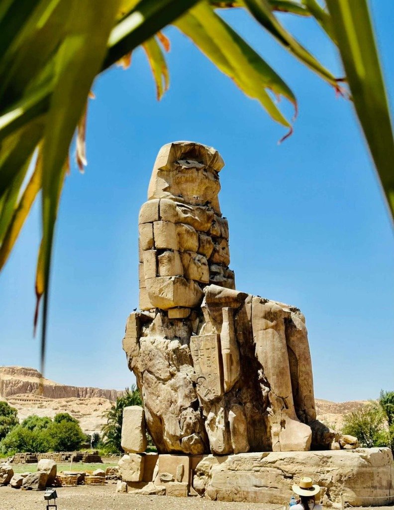 Die geheimnisvollen Memnonkolosse gerahmt von Palmen in Luxor